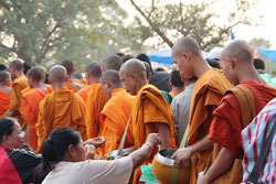 These people are giving donations to Buddhist monks in Laos. Altruism is very unusual in primates, but humans often act altruistically. Image by GuillaumeG.