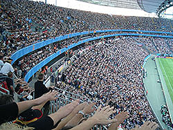 Spectators at a sporting event use human nature to make the wave. You stand up when those closest to you stand and lift your arms up. You sit down when they do. That helps to create the illusion of a wave ripple going around the stadium.