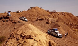 A caravan of trucks carry people and supplies through the dusty hills to a field site in Hadar, Ethiopia. Image by Benjamin Reed.